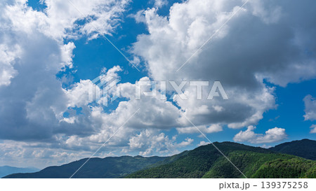 真夏の青空に流れるたくさんの白い雲と、緑に包まれた山々 真夏の青空に流れるたくさんの白い雲と、緑に包まれた山々 139375258