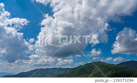 真夏の青空に流れるたくさんの白い雲と、緑に包まれた山々 139375294