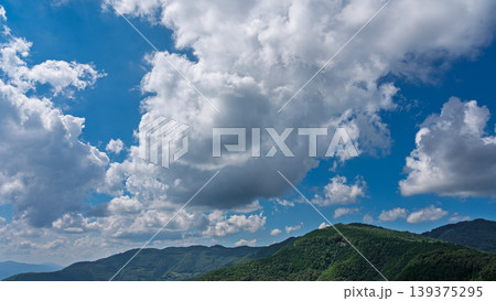 真夏の青空に流れるたくさんの白い雲と、緑に包まれた山々 真夏の青空に流れるたくさんの白い雲と、緑に包まれた山々 139375295