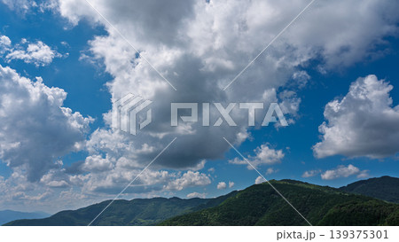 真夏の青空に流れるたくさんの白い雲と、緑に包まれた山々 真夏の青空に流れるたくさんの白い雲と、緑に包まれた山々 139375301