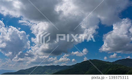 真夏の青空に流れるたくさんの白い雲と、緑に包まれた山々 真夏の青空に流れるたくさんの白い雲と、緑に包まれた山々 139375311