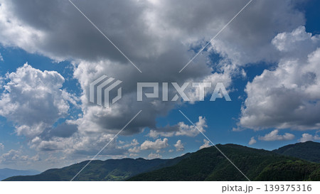 真夏の青空に流れるたくさんの白い雲と、緑に包まれた山々 真夏の青空に流れるたくさんの白い雲と、緑に包まれた山々 139375316