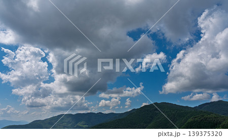 真夏の青空に流れるたくさんの白い雲と、緑に包まれた山々 真夏の青空に流れるたくさんの白い雲と、緑に包まれた山々 139375320