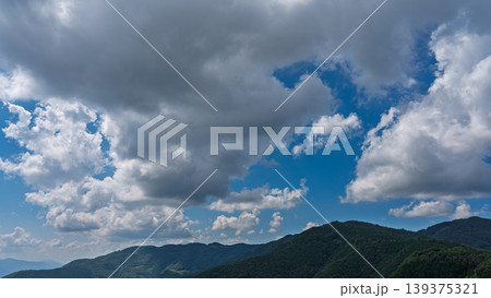 真夏の青空に流れるたくさんの白い雲と、緑に包まれた山々 真夏の青空に流れるたくさんの白い雲と、緑に包まれた山々 139375321