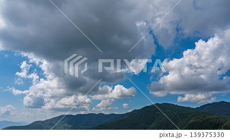 真夏の青空に流れるたくさんの白い雲と、緑に包まれた山々 真夏の青空に流れるたくさんの白い雲と、緑に包まれた山々 139375330