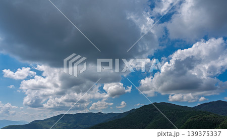 真夏の青空に流れるたくさんの白い雲と、緑に包まれた山々 真夏の青空に流れるたくさんの白い雲と、緑に包まれた山々 139375337