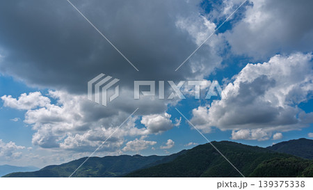 真夏の青空に流れるたくさんの白い雲と、緑に包まれた山々 真夏の青空に流れるたくさんの白い雲と、緑に包まれた山々 139375338