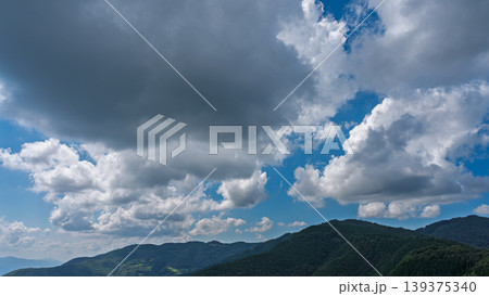 真夏の青空に流れるたくさんの白い雲と、緑に包まれた山々 真夏の青空に流れるたくさんの白い雲と、緑に包まれた山々 139375340