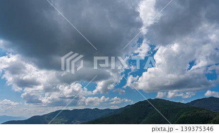 真夏の青空に流れるたくさんの白い雲と、緑に包まれた山々 真夏の青空に流れるたくさんの白い雲と、緑に包まれた山々 139375346