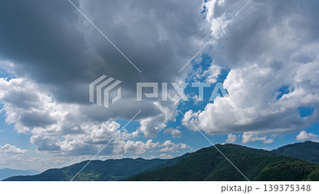 真夏の青空に流れるたくさんの白い雲と、緑に包まれた山々 真夏の青空に流れるたくさんの白い雲と、緑に包まれた山々 139375348