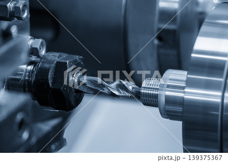 Precision hole making process on a CNC lathe machine using a high-speed drill tool in a blue-toned industrial scene. Precision hole making process on a CNC lathe machine using a high-speed drill tool in a blue-toned industrial scene. 139375367