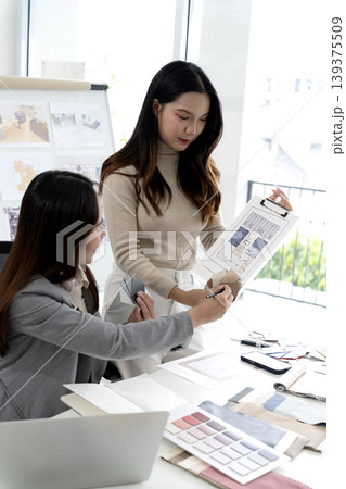 Two female interior designers discussing renovation ideas with blueprints Two female interior designers discussing renovation ideas with blueprints 139375509