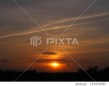 オレンジ色に染まる夕焼け空と横切るひこうき雲と沈みゆく太陽 オレンジ色に染まる夕焼け空と横切るひこうき雲と沈みゆく太陽 139376487