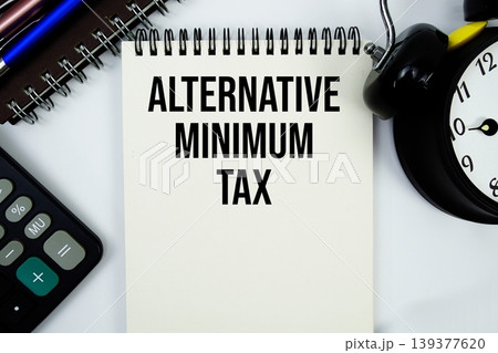 Alternative Minimum Tax text written on notepad with calculator and alarm clock 139377620