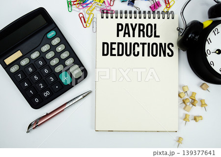 Payroll Deductions text written on notepad with calculator and alarm clock Payroll Deductions text written on notepad with calculator and alarm clock 139377641