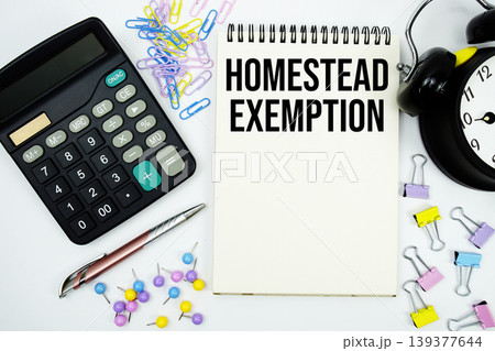 Homestead Exemption text written on notepad with calculator and alarm clock 139377644