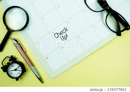 Check Up! message written on calendar date with alarm clock, glasses and magnifying glass on yellow background 139377661