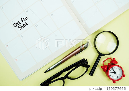 Get Flu Shot message written on calendar date with alarm clock, glasses and magnifying glass on yellow background Get Flu Shot message written on calendar date with alarm clock, glasses and magnifying glass on yellow background 139377666