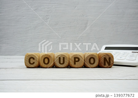 COUPON alphabet letters with calculator on wooden background COUPON alphabet letters with calculator on wooden background 139377672
