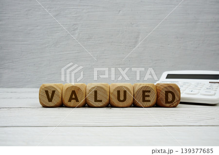 VALUED alphabet letters with calculator on wooden background VALUED alphabet letters with calculator on wooden background 139377685