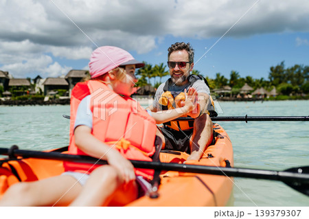 Father kayaking with daughter on calm sea during family summer vacation. Father kayaking with daughter on calm sea during family summer vacation. 139379307