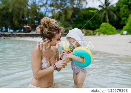 Mother playing in sea water with little daughter. Mother playing in sea water with little daughter. 139379308