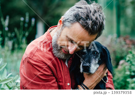 Man hugging senior dog with affection. Man hugging senior dog with affection. 139379358