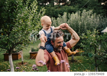 Father holding baby daughter while spending time together in garden. 139379409