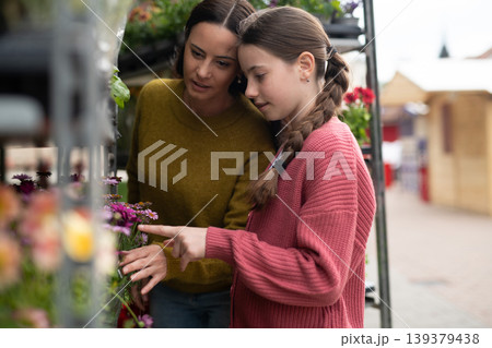 Mother and daughter choosing flowers at market. 139379438