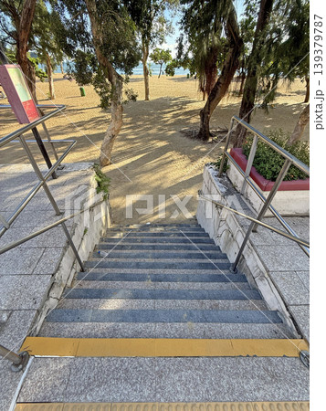 Descending stone staircase leading to a sunlit sandy beach with trees Descending stone staircase leading to a sunlit sandy beach with trees 139379787