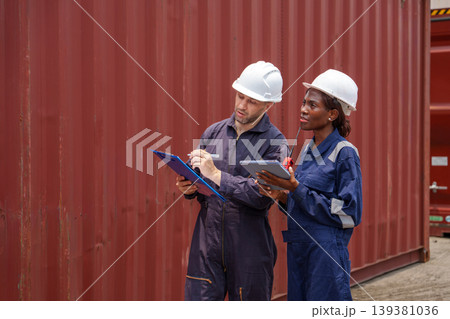 Professional industrial workers checking inventory on electronic device and clipboard for supply chain management at an Asian shipping terminal 139381036