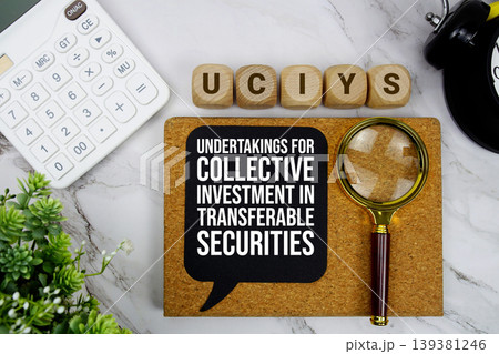 UCITS Undertakings for Collective Investment in Transferable Securities text with calculator, magnifying glass and alarm clock on marble background 139381246