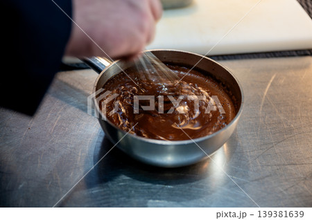 Baker stirs velvety hot chocolate with reflections highlighting cozy comfort atmosphere Baker stirs velvety hot chocolate with reflections highlighting cozy comfort atmosphere 139381639