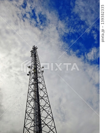 Telecommunication tower against a dramatic cloudy sky during sunset. 139382335