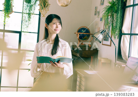 自宅の部屋で手帳を持って微笑む若い日本人女性 自宅の部屋で手帳を持って微笑む若い日本人女性 139383283