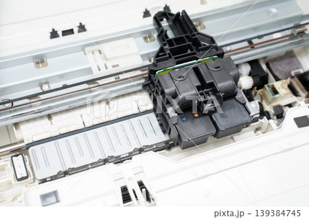 Close-up open inkjet printer showing the printhead and cartridge assembly on rails, internal hardware, mechanisms and parts for repair, maintenance, diagnostics and technical documentation. Close-up open inkjet printer showing the printhead and cartridge assembly on rails, internal hardware, mechanisms and parts for repair, maintenance, diagnostics and technical documentation. 139384745