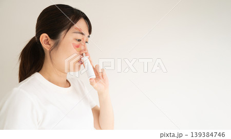 Asian woman face with nasal sinuses anatomy using nasal spray suspension for relieve symptoms such as sneezing, runny or itchy nose. Medical device used to treat allergic rhinitis, hay fever, 139384746