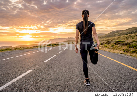 夕焼けの道路でストレッチする女性ランナー 夕焼けの道路でストレッチする女性ランナー 139385534