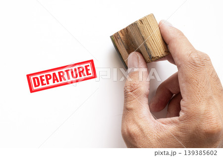 Hand pressing wooden rubber stamp with red Departure text on white paper surface, travel immigration concept Hand pressing wooden rubber stamp with red Departure text on white paper surface, travel immigration concept 139385602