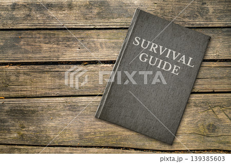 Survival Guide book cover on rustic wooden table background, outdoor adventure emergency preparedness concept 139385603