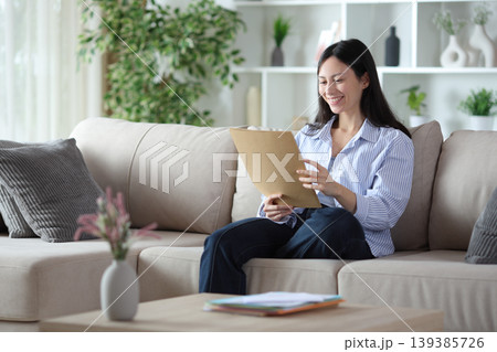 Asian woman checking paper document on a sofa at home 139385726