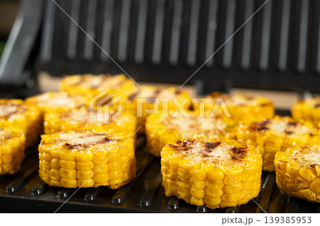 Appetizing Yellow Corn Rounds Grilling on Indoor Contact Grill Appetizing Yellow Corn Rounds Grilling on Indoor Contact Grill 139385953