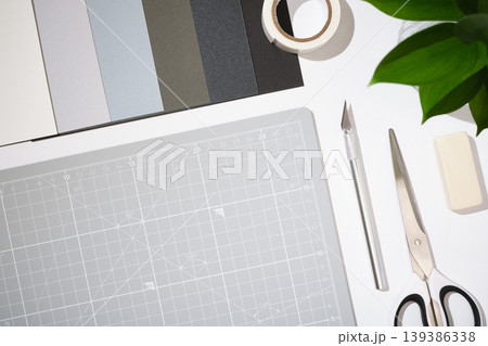 Craft workspace with cutting mat, utility knife, scissors, color samples and stationery on clean white background. Copyspace Craft workspace with cutting mat, utility knife, scissors, color samples and stationery on clean white background. Copyspace 139386338