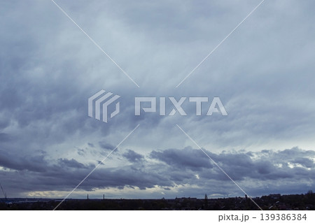 Stormy dark thunderclouds gather in the gloomy sky over the city. Cloudy sky with dark gray rain clouds. 139386384