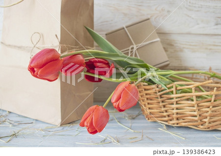 Red tulips in a brown paper bag on a wooden background, fresh spring flowers for interior decoration Red tulips in a brown paper bag on a wooden background, fresh spring flowers for interior decoration 139386423