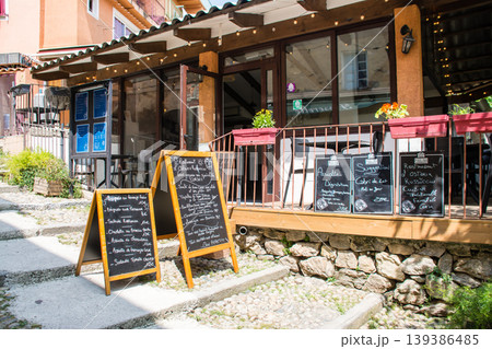パステルカラーの建物とレストランの店先に置かれたイスとテーブル　地中海のフランス領のコルシカ島にて 139386485
