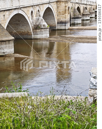Ancient arched stone bridge reflected in the calm river water.  139386817
