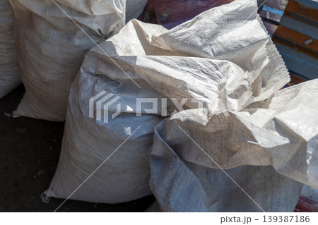 Bags filled with construction waste are stacked at a construction site. The location is busy with activity during daylight hours Bags filled with construction waste are stacked at a construction site. The location is busy with activity during daylight hours 139387186