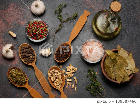 Spices on a dark background in wooden spoons: pepper, cloves, ginger, allspice and bay leaf, salt Spices on a dark background in wooden spoons: pepper, cloves, ginger, allspice and bay leaf, salt 139387466