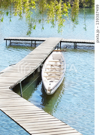 An old white boat near a wooden bridge. Summer landscape. An old white boat near a wooden bridge. Summer landscape. 139387499
